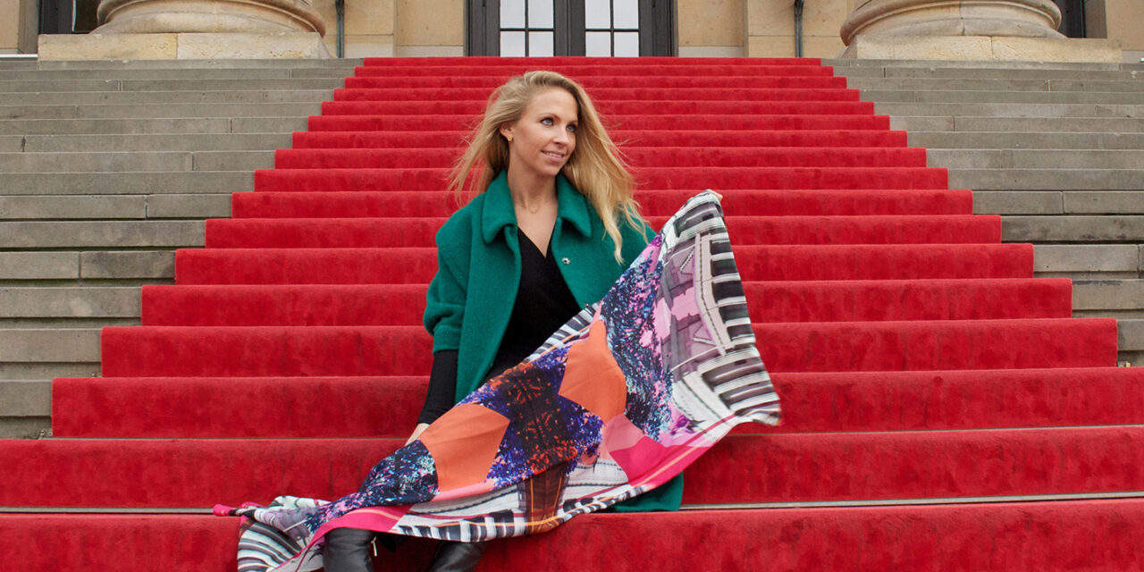 Women holding a silk-scarf on stairs with a red carpet